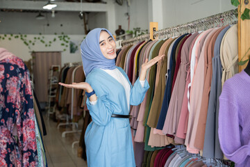 A girl in a veil with her hands shows something while standing inside a boutique shop