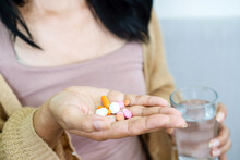 closeup handful of medicines, hand woman hand taking overdose pills with glass of water