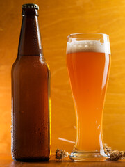 Wall Mural - A tall glass of a pint of beer on a wooden table, a beer bottle. Unfiltered traditional wheat beer