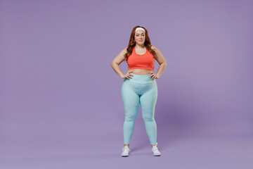 Full length young chubby overweight plus size big fat fit woman wear red top warm up training stand akimbo arm on waist isolated on purple background studio home gym. Workout sport motivation concept.