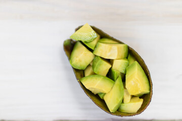 Wall Mural - Sliced avocado isolated on white wooden table background; top view.