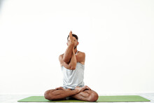 Male yoga maditates in classical pose in studio over white background