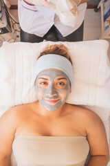 Poster - Smiley young female with a partly wiped off clay mask on her face