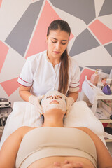 Poster - Young female getting face care Spa treatment with the sheet mask by a qualified specialist