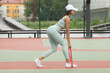 Fitness black girl workout with fitness elastic bands in green tracksuit outdoors.