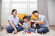 © comzeal - Happy Asian family playing with wooden bricks in living room, Lifestyle relaxing at home concept