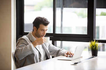 businessman working on laptop while drinking coffee in the office.