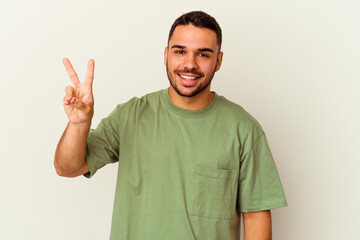 Young caucasian man isolated on white background joyful and carefree showing a peace symbol with fingers.