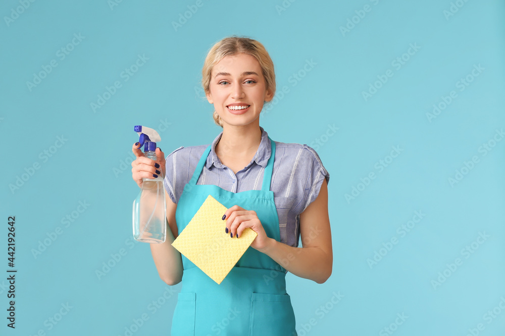 Young woman with detergent and cloth on color background