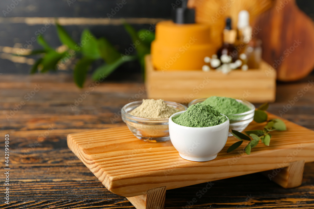 Bowls with henna powder on wooden background