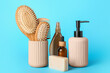 Hair brushes, comb and cosmetics on color background