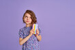 © zamuruev - Little girl holding telephone isolated over violet color background