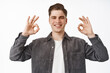 Fine, very well. Smiling satisfied young man, guy show white teeth, okay zero sign, OK agree and praise something good, like and approve, white background