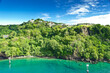 Coastline at Kingstown on Saint Vincent, steep cliff covered by trees behind turquoise and emerald colored water