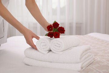 Canvas Print - Chambermaid putting flowers with fresh towels in hotel room, closeup