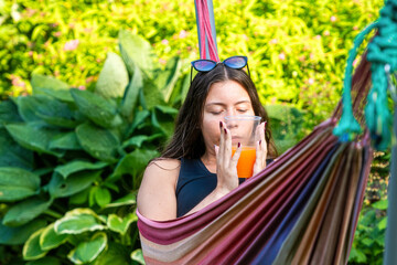 Wall Mural - gorgeous girl lying on the hammock relaxing and drinking orange juice