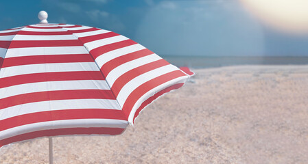 Wall Mural - Part of a striped beach umbrella against a beautiful blue sky, side view.