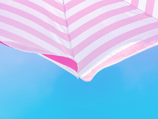 Wall Mural - Part of a striped beach umbrella against a beautiful blue sky, bottom view