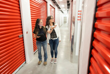 Worker Giving Tour To Woman In Storage Facility Corridor