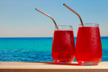 Beach bar, summer sea resort concept. Two summer cherry cocktails made of gin and cherry juice.