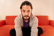 © Angel Gruber - Young latin man portrait sitting on a couch sofa at home in the living room