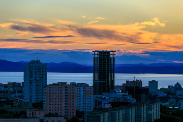 Wall Mural - View from above. Silhouettes of tall residential home on the background of sunset in Vladivostok. New residential neighborhood in the sea city.