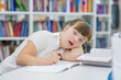 Young girl with syndrome down doing homework at library. Education for disabled children concept