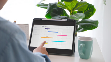 Man looking at time frame planner on digital tablet screen for mobile phone app delveloper team at home office