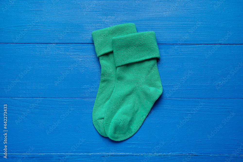 Baby socks on color wooden background
