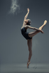 Wall Mural - Professional ballerina dancing in studio against gray background