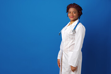 Wall Mural - Portrait of a young african american woman doctor against blue background