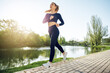 © fotofabrika - Athletic fit young woman jogging early in the morning in park
