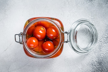 Pickled cherry tomatoes in a glass jar. White background. Top view