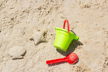 Children Beach Toys Buckets, Spade, Shovel On Sand. Sunny Day On The Seaside. Star And Shell Form