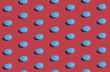 Vibrant colorful pattern of blue medicine pills on red background. Creative concept of overdose medicine usage and addiction to health tests.