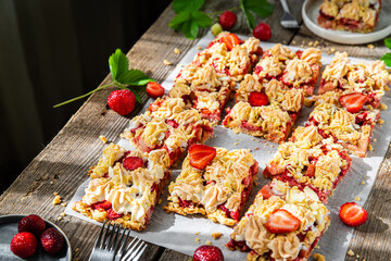 Strawberry and rhubarb meringue crumble sheet pieon baking paper on old wooden table.