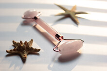 Skincare For Summer – Closeup Of A Rose Quartz Roller And Starfish.