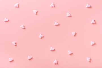 sweet sprinkles of heart shapes over pink background, concept of festive invitation for Valentines day, birthday, holiday and party time