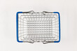 empty metal shiny basket with grocery handles on white wooden table background. close-up