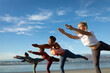 © Wavebreak Media - Group of diverse female friends practicing yoga, stretching at the beach