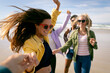 © Wavebreak Media - Happy group of diverse female friends having fun, walking along beach holding hands and laughing