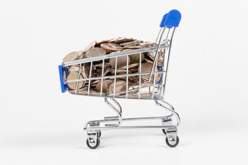 Wall Mural - metal chrome shiny shopping trolley on wheels with nickel plated coins isolated on white background. close-up