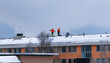 Team male workers with shovels removing snow on the roof of building after snowfall. Orange working uniform. Snow removal, climber cleaning roof in winter. Safety city concept Snowing weather Helsinki
