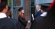 © VAKSMANV - Great moment. Full length view of the teacher giving diploma to the student girl wearing graduation gown and hat. Girl and her group mates rejoicing and celebrating