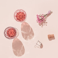 Sticker - Two fashion glasses  of rose wine and small bouquet of flowers on pastel pink background Summer vacation flat lay