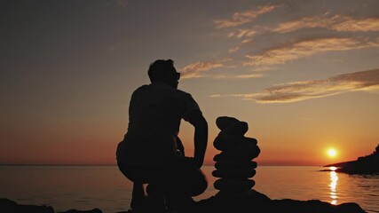 Wall Mural - Silhouette of a man and zen stones on a ocean sea cliff in sunset sunrise time.