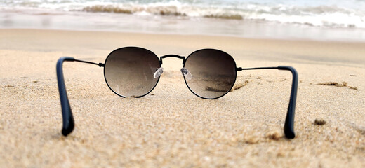 Sun glasses at the sand of the beach near the sea