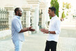 © etonastenka - Happy two multiracial male best friends talking while standing in the street, african guy talking to afghan buddy at outdoor meeting. Smiling multiethnic young people, multicultural friendship reunion
