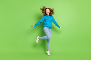 Poster - Full size photo of cheerful young happy small girl fly wind hair smile sportive isolated on green color background