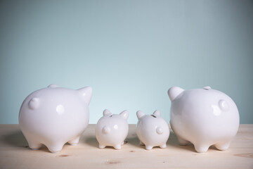 Family white four piggy bank on old wood looking at green background. Father and mother little piggyback training save money for growth in the future. Concept family saving money for the future.